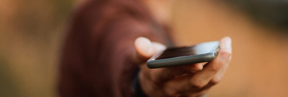 man in brown sweater holding black smartphone